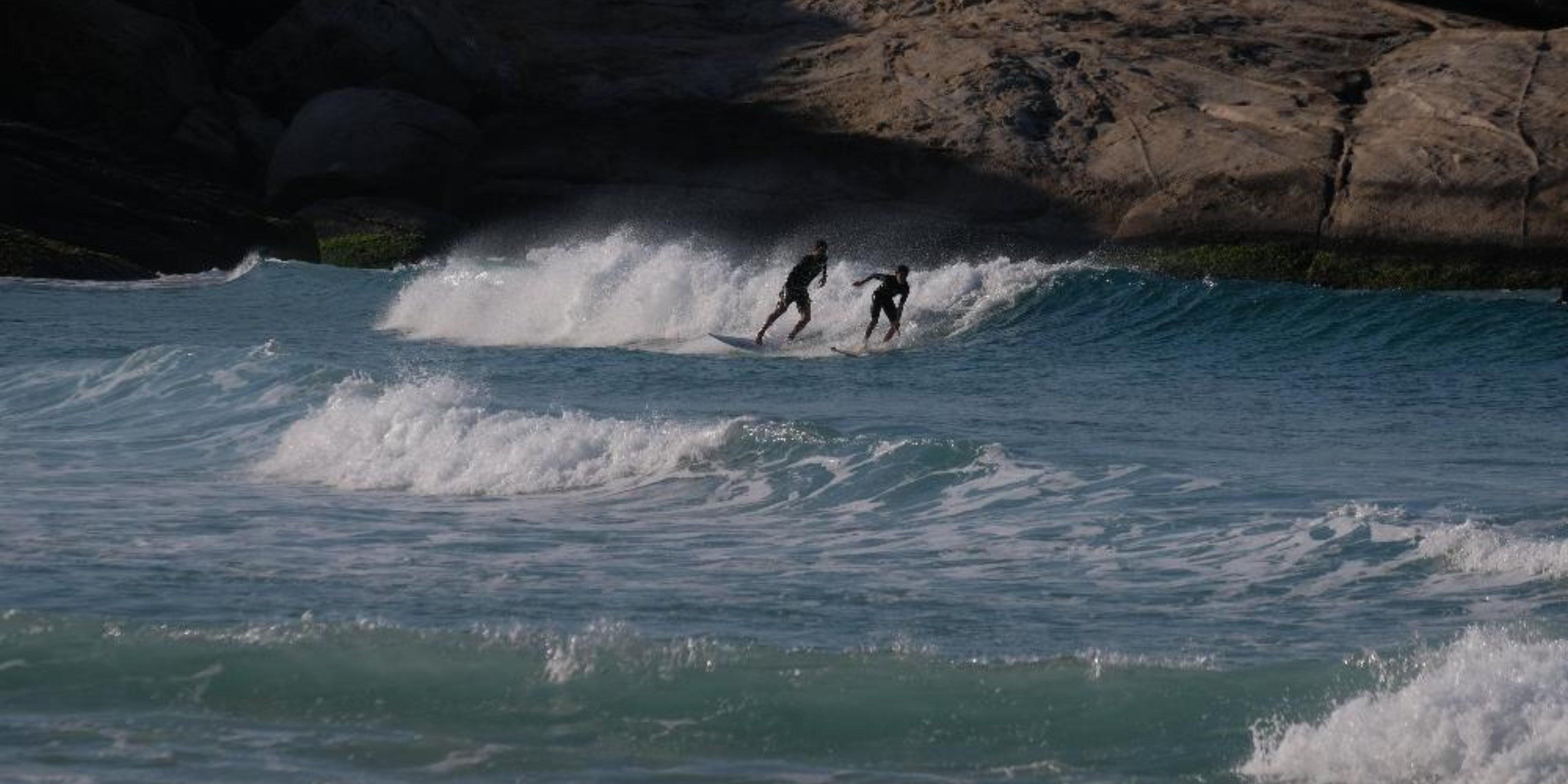 Two people surfing in blue choppy water