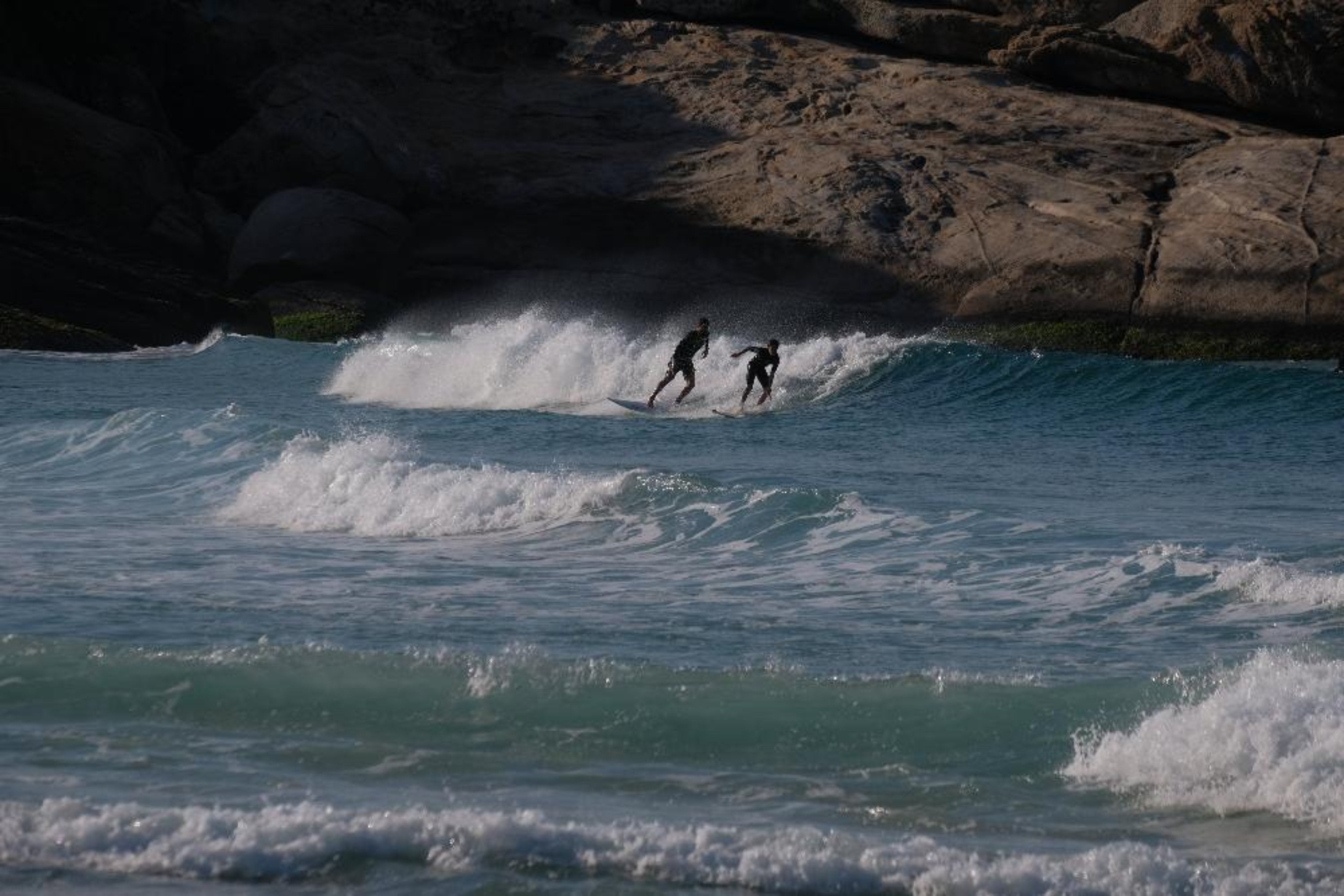 Two people surfing in blue choppy water